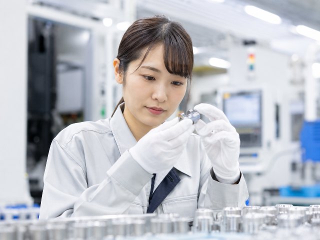 工場内で金属部品を目視で確認する様子